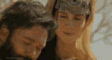 a man and a woman are standing next to each other and the woman is wearing a tiara .