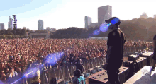 a man stands in front of a crowd at a music festival with a sign that says ' t.i.p. '