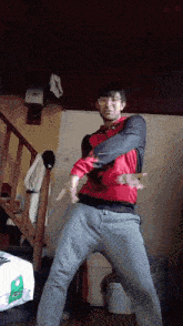 a man in a red jacket is dancing in a room