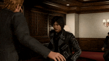 a man in a studded leather jacket is standing next to another man in a suit