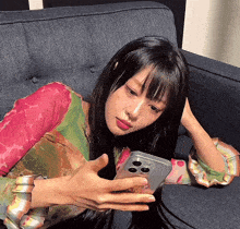 a woman laying on a couch looking at her phone with a sticker on it that says ' a ' on it