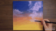 a person is painting a sunset on a canvas with the words made in animotica below it