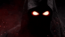 a hooded figure with red eyes and flames coming out of its mouth .