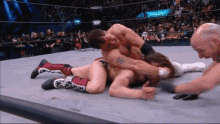 two men are wrestling in a ring with a sign that says evolution in the back