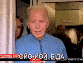 a man in a blue jacket stands in front of a breaking news screen
