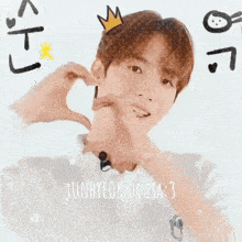 a young man is making a heart shape with his hands with a crown on his head .