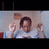 a woman wearing glasses and a t-shirt that says stemminds is sitting on a couch reading a book