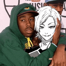 a man in a green hoodie holds a drawing of a woman