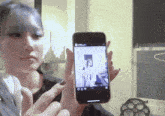 a woman is holding up a cell phone with a picture of a woman on it