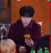 a man is sitting at a table holding a piece of food in his hand .