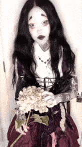 a woman in a purple dress is holding a white flower
