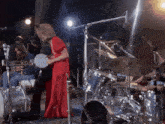 a woman in a red dress plays a drum on stage