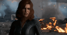 a woman in a black suit stands in front of fire