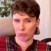 a close up of a man wearing a plaid shirt and a hat making a funny face .