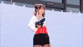 a girl in a red top and black skirt is surrounded by pink and white sparkles