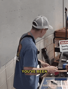 a man in a blue shirt is standing in front of a sign that says " you 've been "