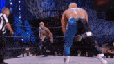 a wrestler with the letter t on his back is standing in a wrestling ring