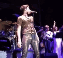 a man is singing into a microphone in front of a yamaha drum set