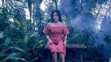 a woman in a pink dress is sitting on a bench