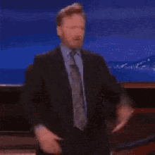a man in a suit is giving two thumbs up
