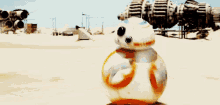 bb-8 , a robot from star wars , is rolling on the ground in the desert .