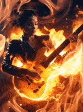 a woman in a leather jacket is playing a guitar surrounded by flames .
