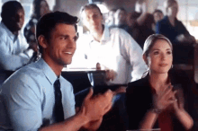a man and a woman are clapping their hands in a crowd