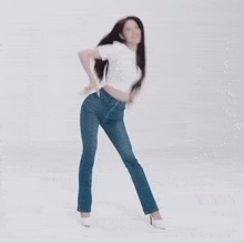 a woman in a white t-shirt and blue jeans is dancing .