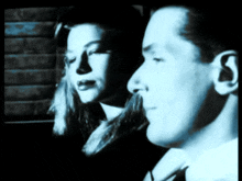 a man and a woman are looking out a window in a black and white photo