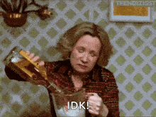 a woman is pouring a drink into a pitcher and saying " idk "