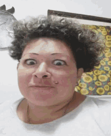 a woman with curly hair is making a funny face in front of a picture of sunflowers