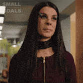 a woman wearing a choker is standing in front of a small achievable goals advertisement