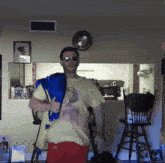 a man wearing sunglasses and a yellow shirt is standing in front of a kitchen counter