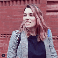 a woman with pink hair is wearing a plaid jacket