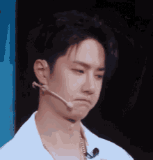a young man with a microphone on his ear making a face