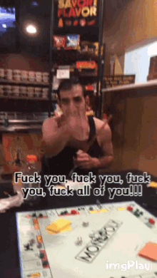 a man sitting at a table with a monopoly board says fuck you fuck you fuck you fuck all of you