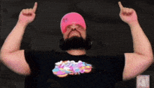 a man wearing headphones and a pink hat is flexing his arms