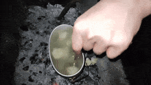 a person is stirring a pot of water with a wooden spoon .