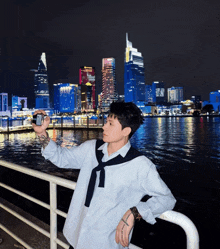 a man taking a picture of a city skyline with a sign that says ' saigon ' on it