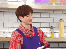 a man in a plaid shirt and blue apron is smiling