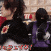 a woman in a black shirt is standing next to another woman in a purple vest with the letters eee on it