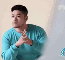 a man wearing a blue sweater is making a heart with his hands