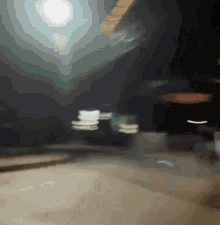 a blurry picture of a street at night with a green sign in the background