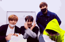 a group of young men are posing for a picture with a cake in the background