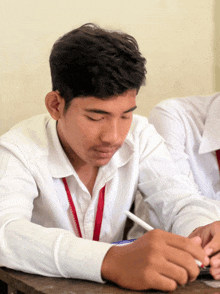 a boy in a white shirt with a red lanyard around his neck