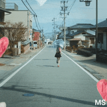 a person walking down a street with an umbrella and the word ms on the bottom right