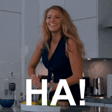 a woman in a blue dress is smiling in a kitchen with the word ha on the bottom