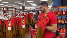 a man in a red shirt is looking at clothes in a store with a sign that says subscribe