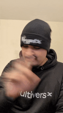 a man wearing a black cultivars hoodie and a black hat