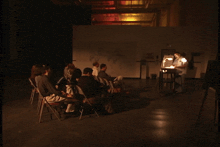 a group of people are gathered in a dark room watching a robot being built